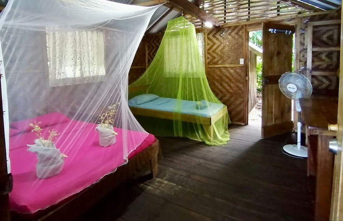 Guest bedroom with traditional woven walls and mosquito netting.