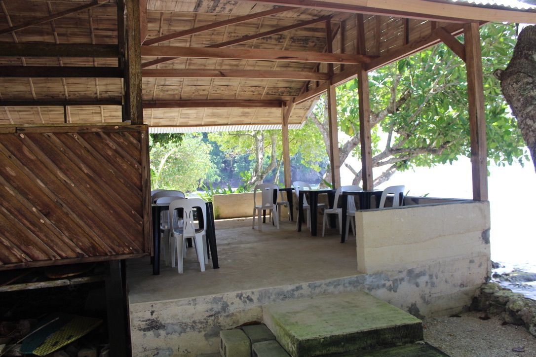 Open-air dining hall with views toward the ocean and trees.