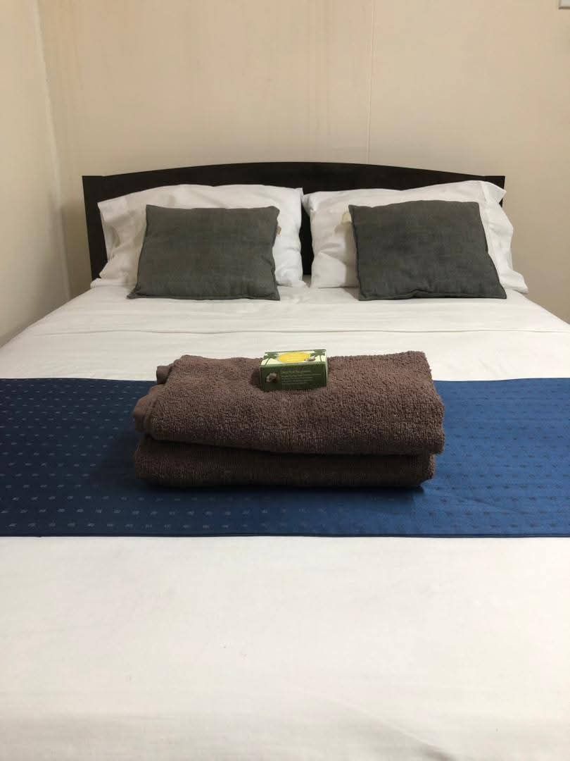 Close-up of a made double bed with fresh towels and guest toiletries.