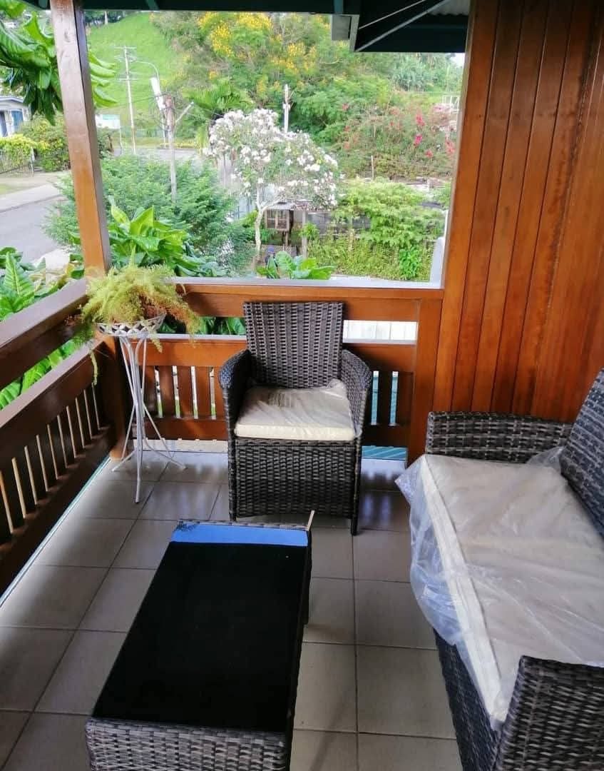 Outdoor balcony seating area featuring wicker furniture and garden views.