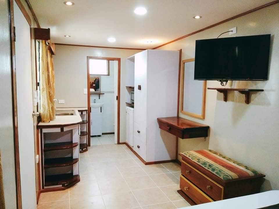 Hotel room interior showing flat-screen TV, storage, and tile flooring.