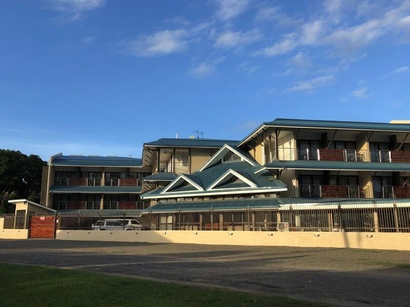 Multi-story accommodation building with pitched roofs and a fenced perimeter.