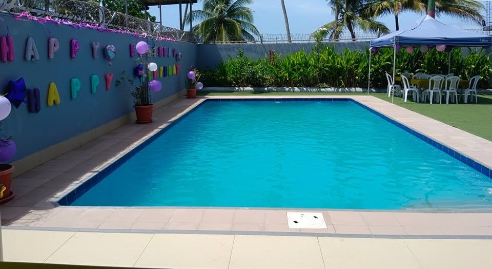 Outdoor rectangular swimming pool with an adjacent event tent and seating area.