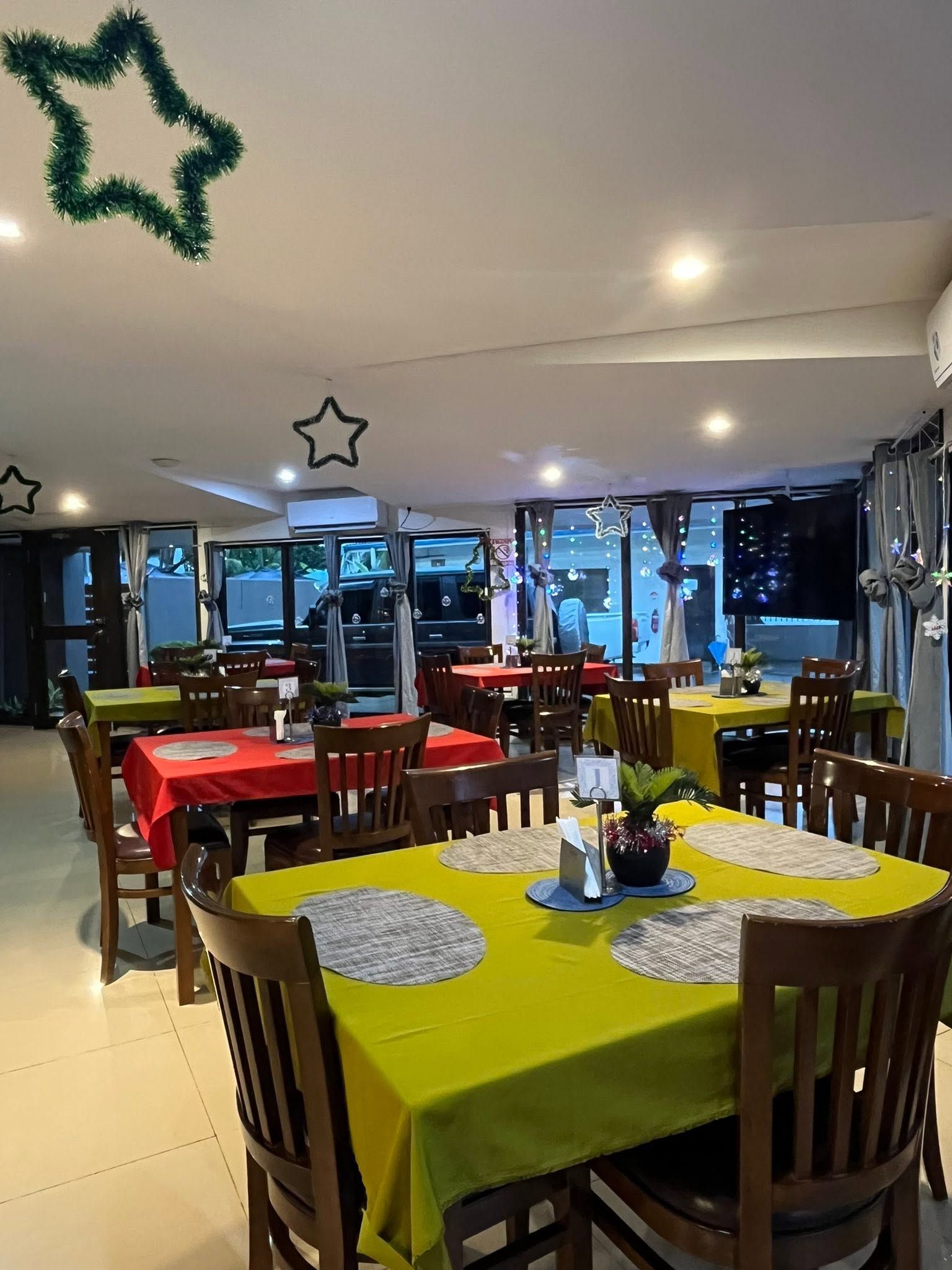 Indoor dining facility with red and green table linens and festive decorations.