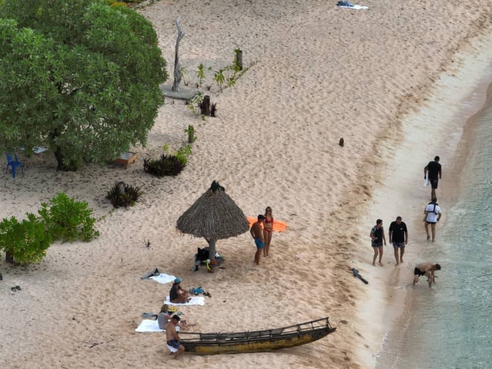 High-angle view of tourists relaxing on a white sand coastline.