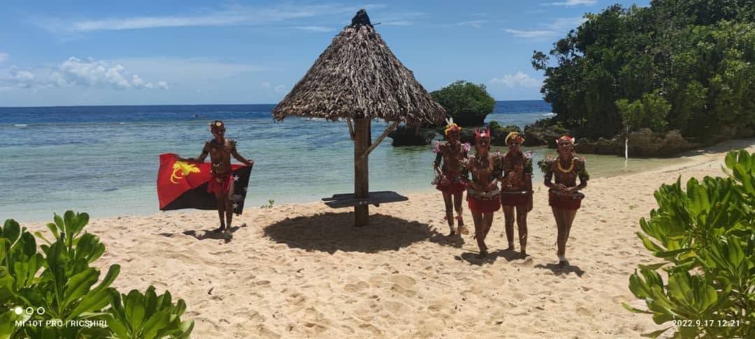 Cultural dancers posing with the national flag on the resort beach.