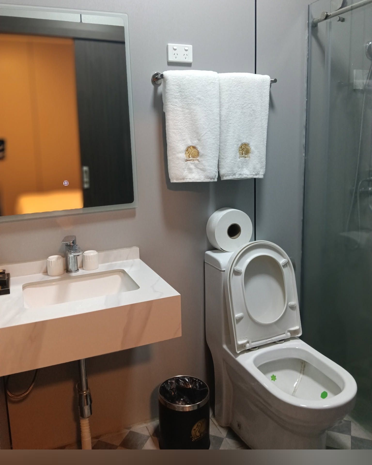 Clean bathroom featuring a marble vanity, sink, toilet, and glass shower partition.