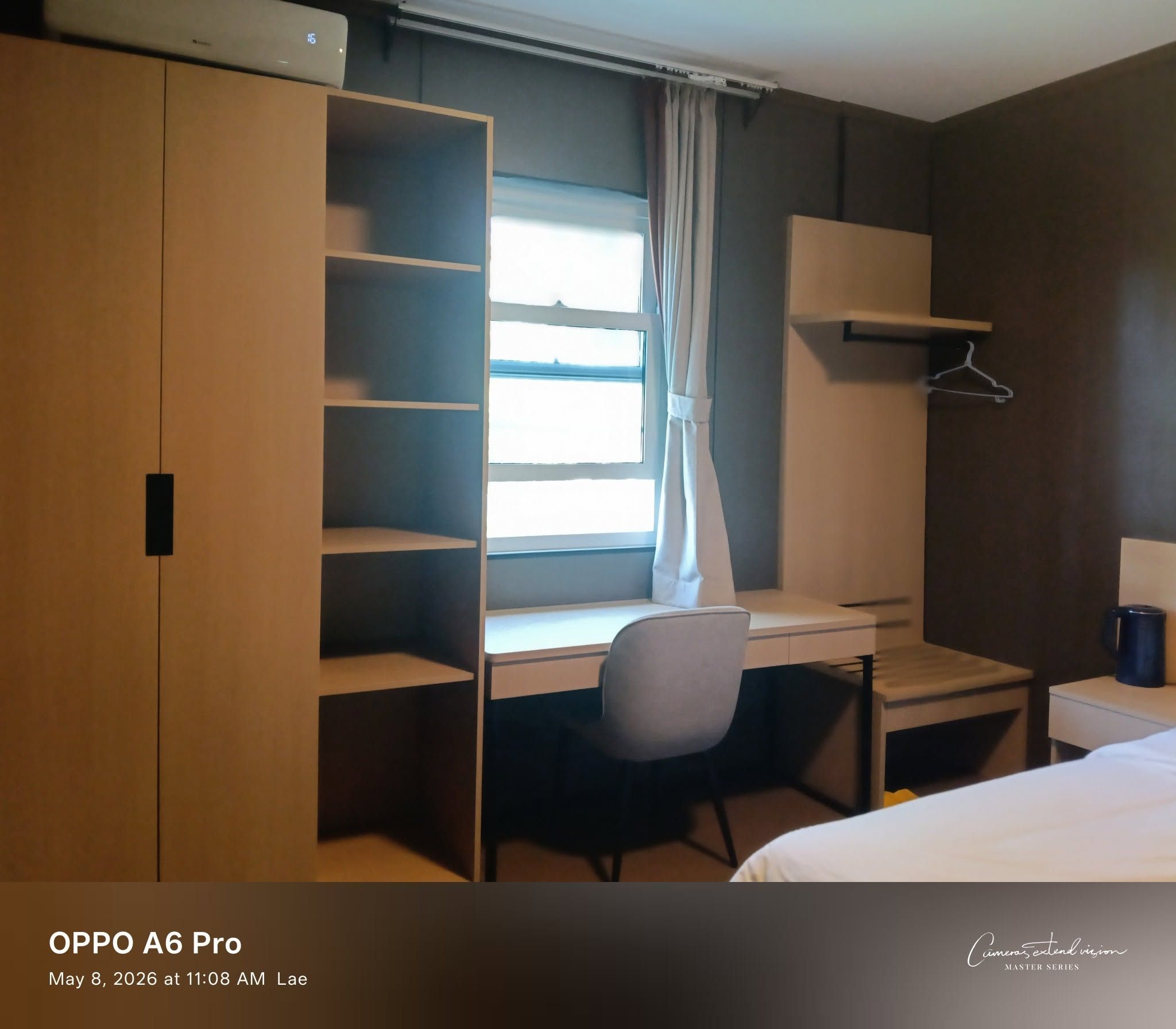 In-room workspace featuring a light-toned wooden desk, chair, and large wardrobe.