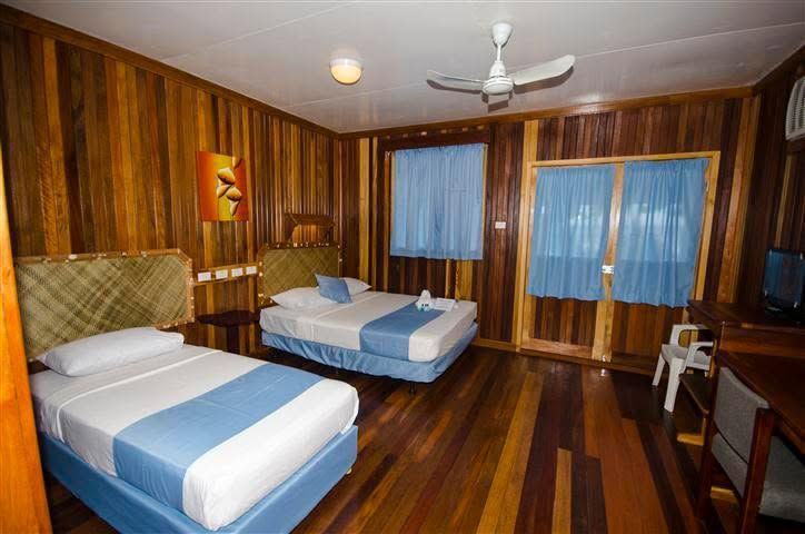 Twin bedroom with wooden paneling and blue curtains