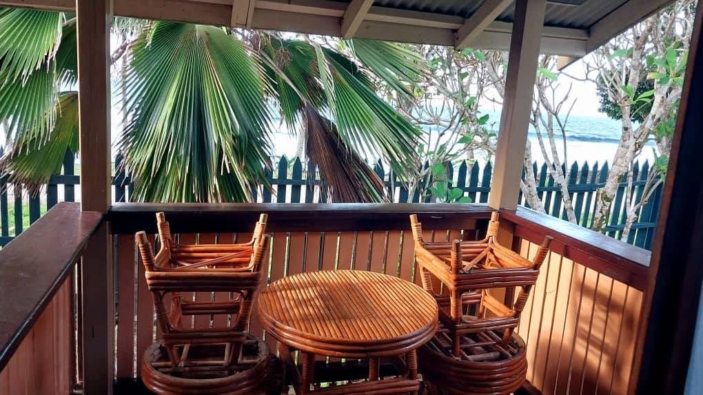 Wooden balcony with table and chairs overlooking the garden and sea
