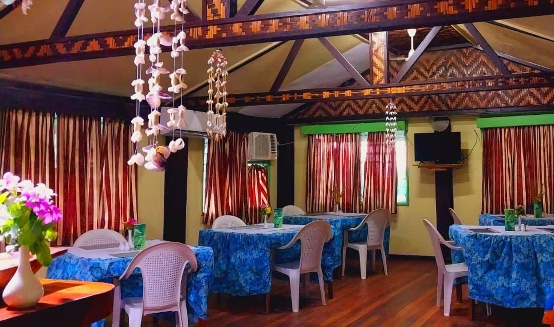 Indoor dining room with blue tablecloths and hanging shell decorations
