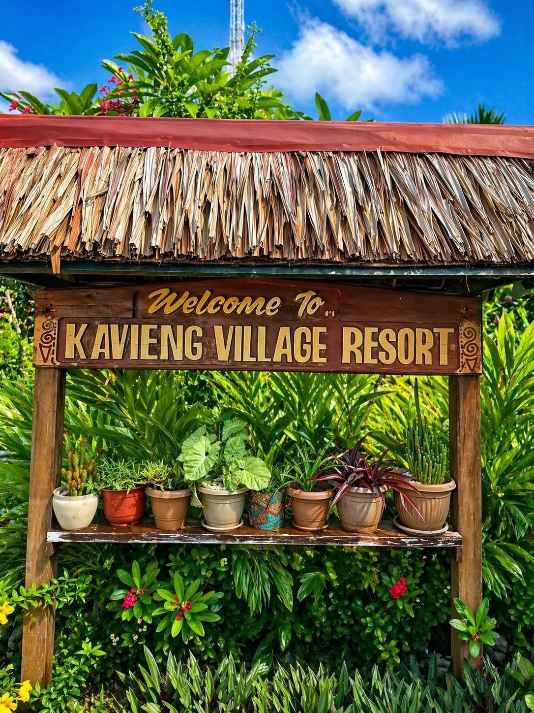 Welcome sign for Kavieng Village Resort surrounded by lush tropical plants