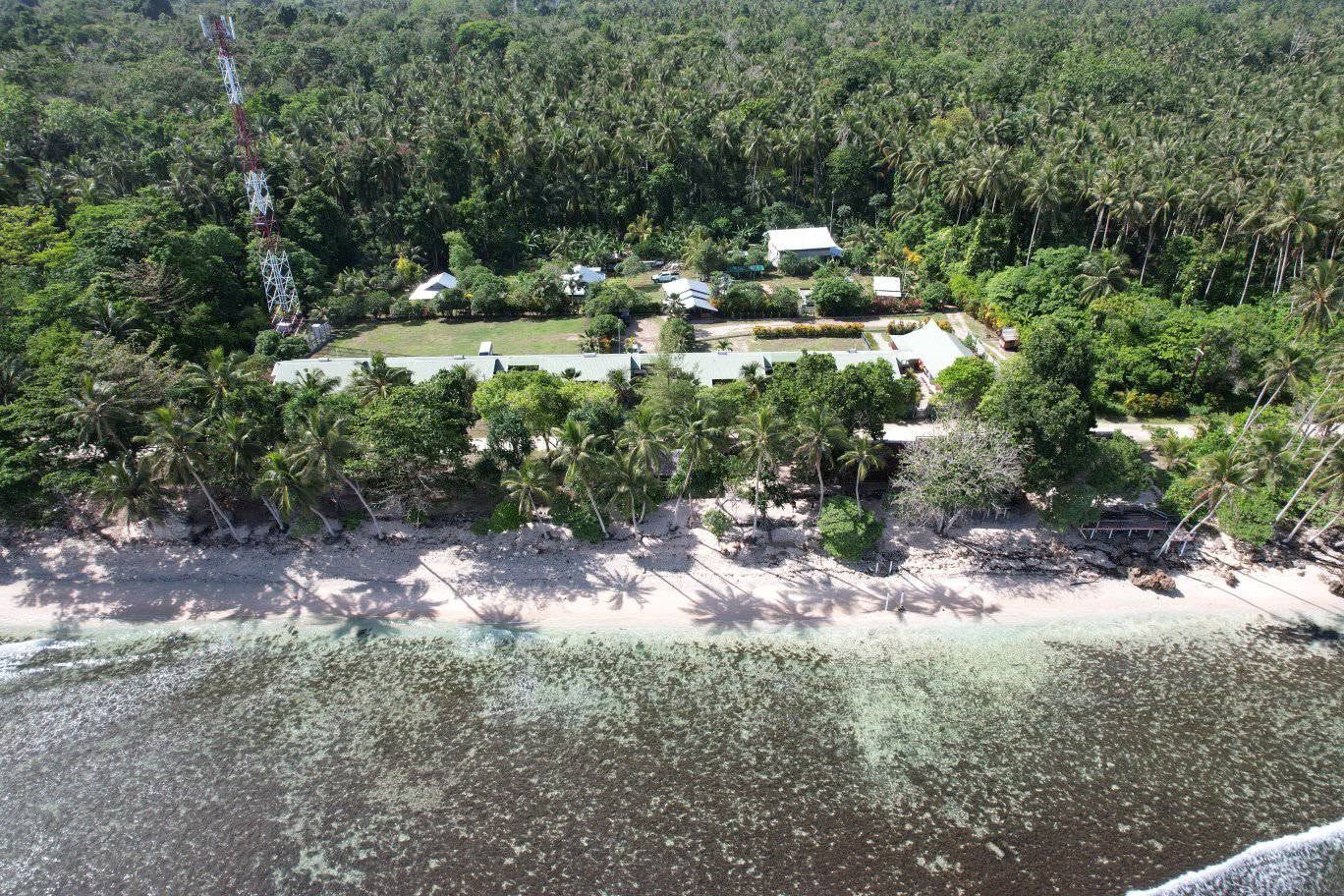 Aerial view of the resort buildings and coastline surrounded by dense forest