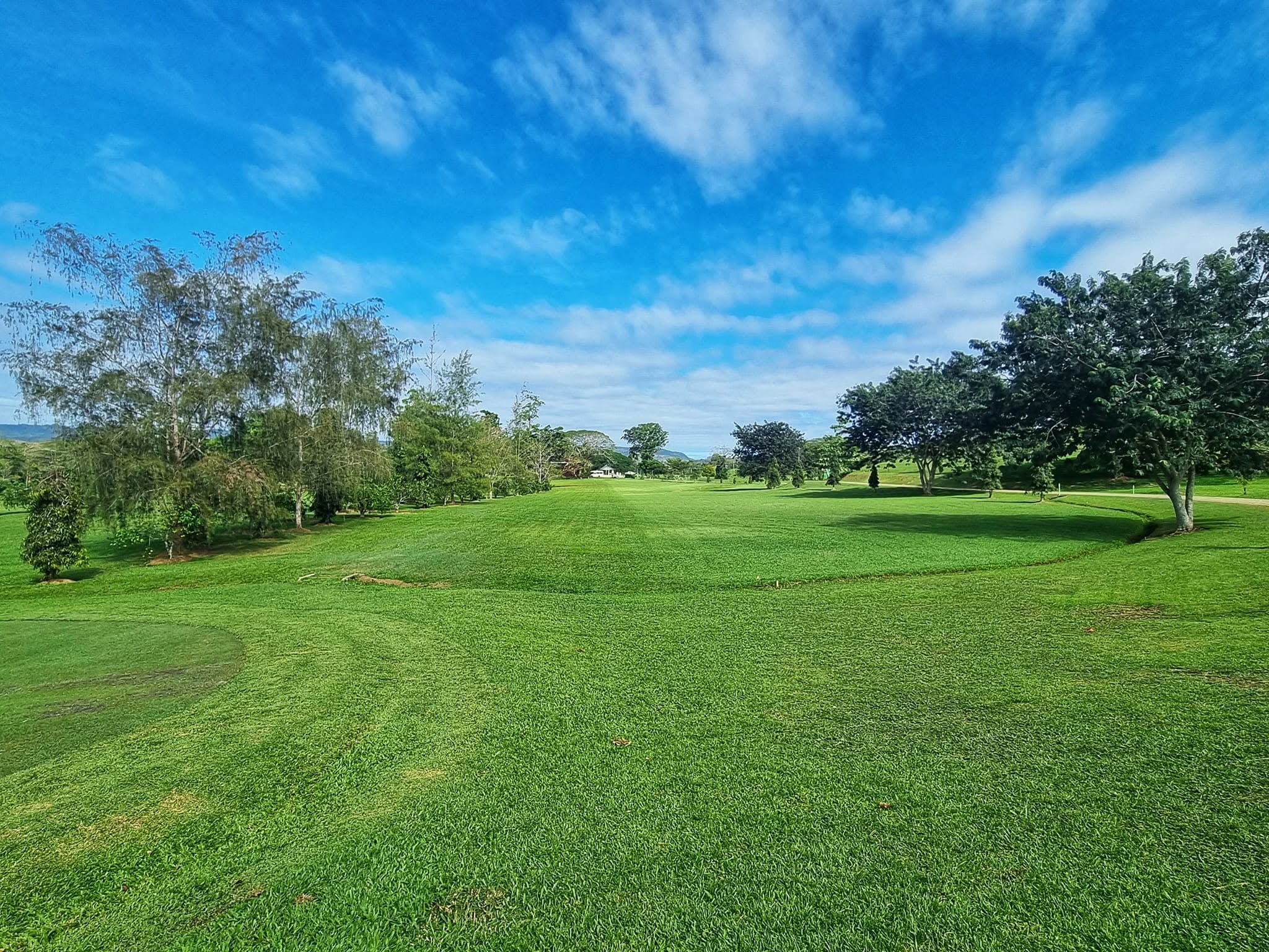 Wide open green space and fairway under a clear blue sky.