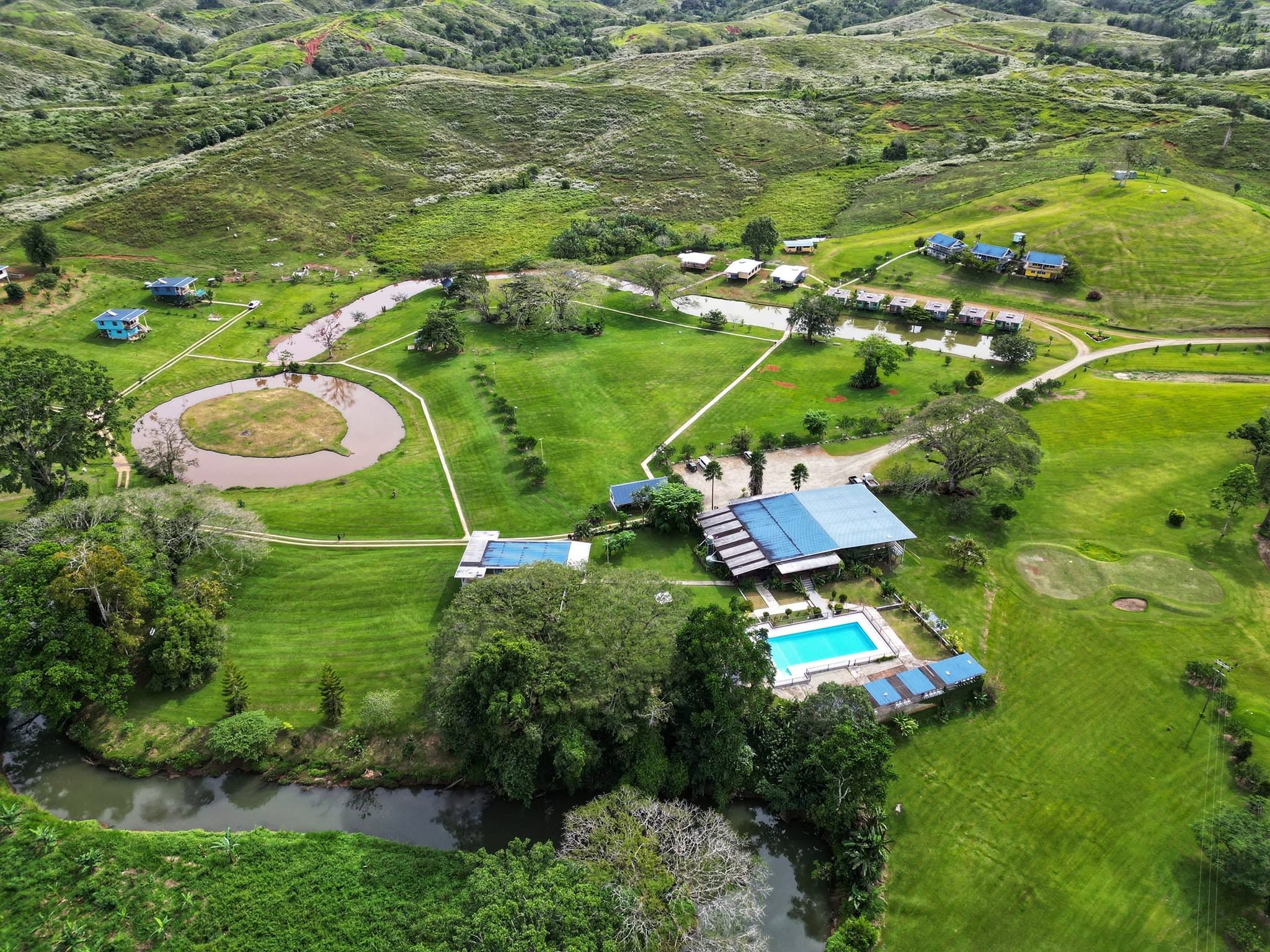 Overhead drone shot showing the swimming pool, buildings, and ponds.
