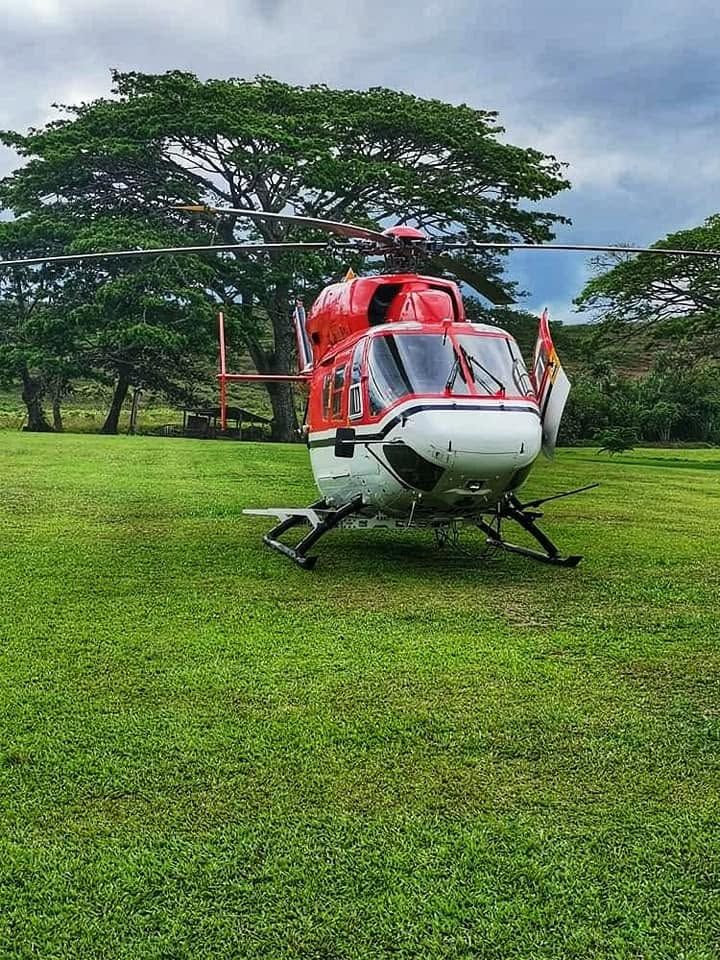 A red and white helicopter parked on the grass field of the club.