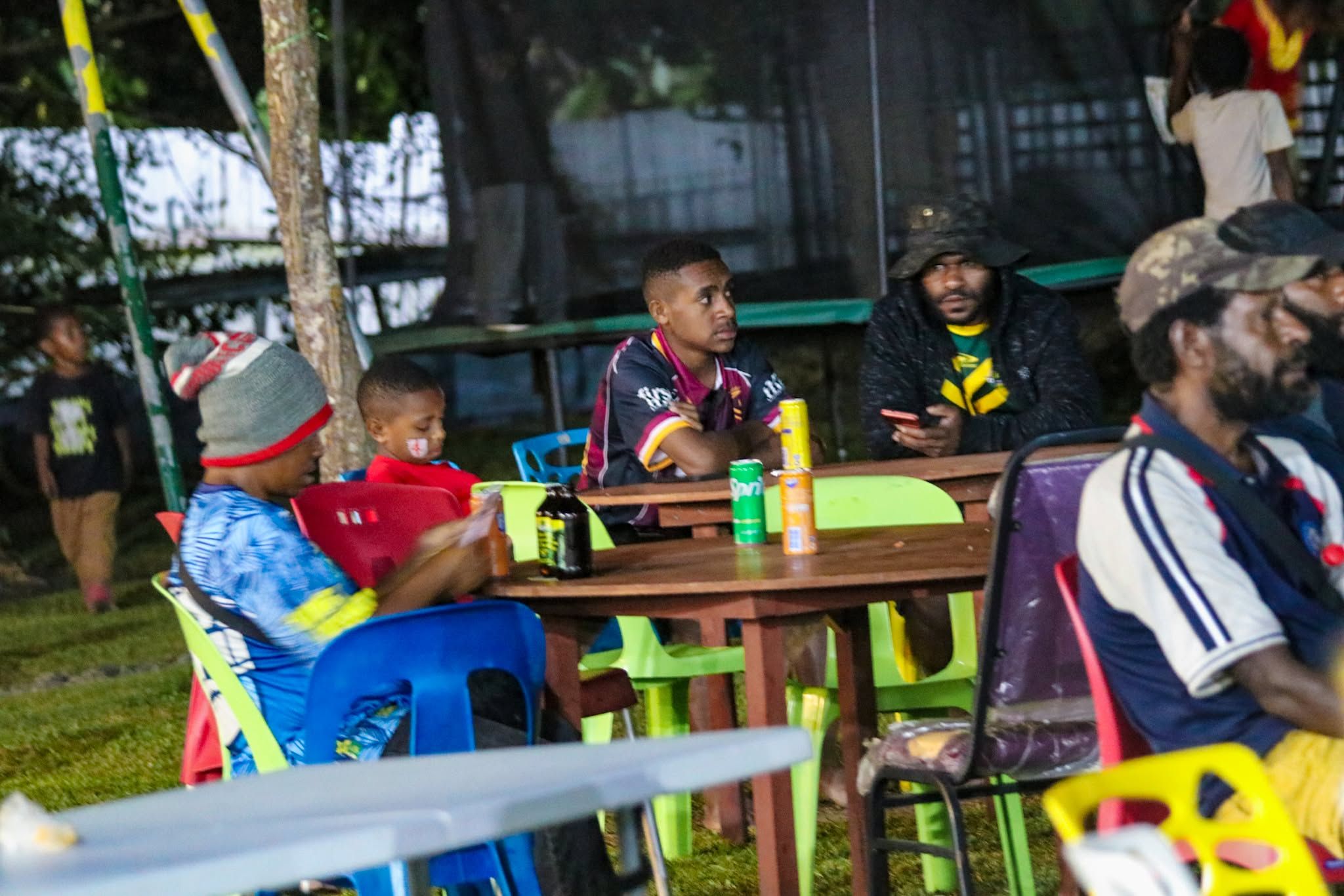 Families gathered at outdoor wooden tables during a night event