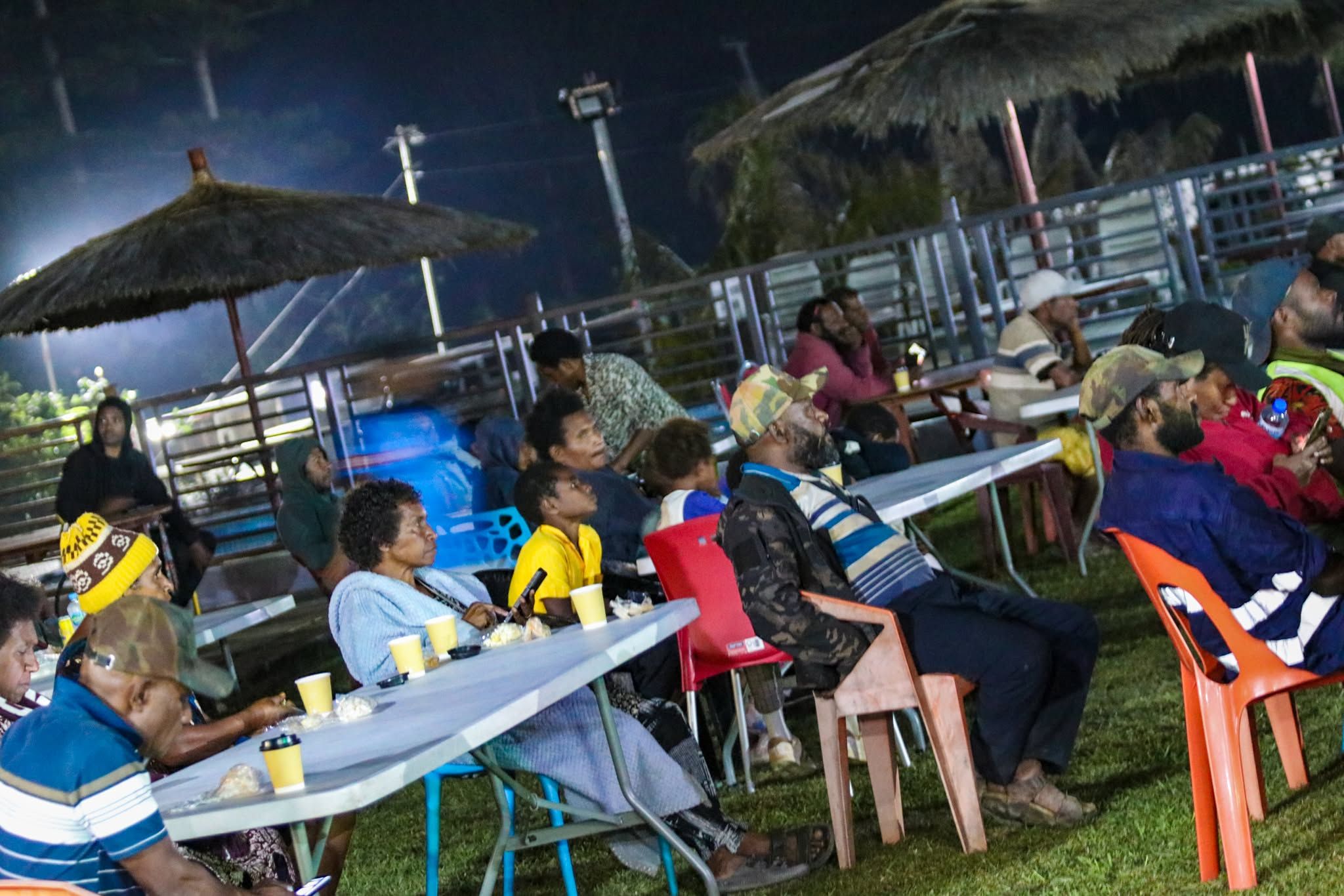 Seated outdoor dining area with thatched umbrellas at night