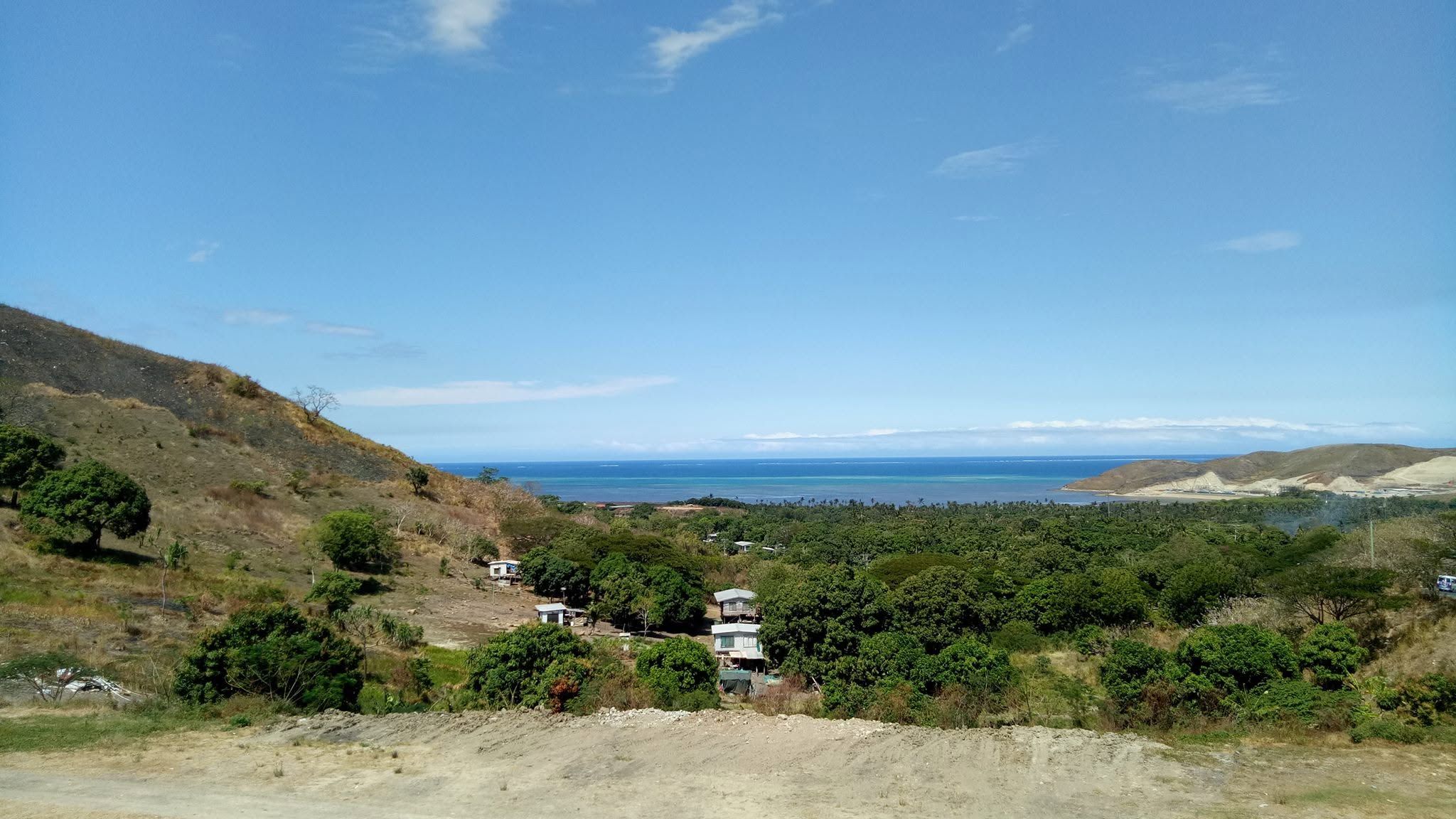 Scenic coastline with turquoise waters and surrounding green hills.