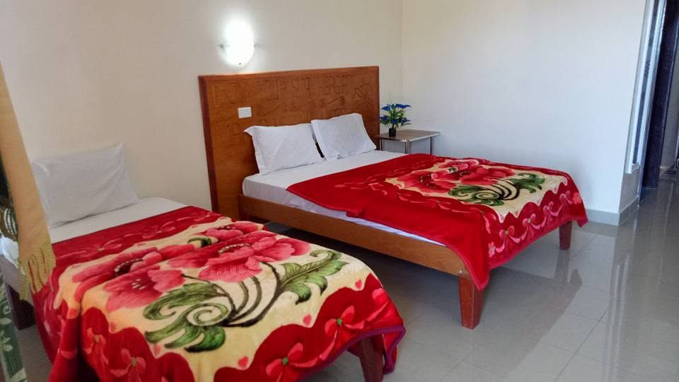 Guest room featuring two beds with floral patterned red blankets.