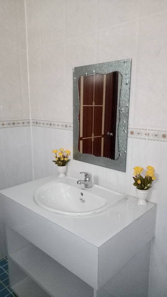 White bathroom vanity and sink area with a decorative mirror.