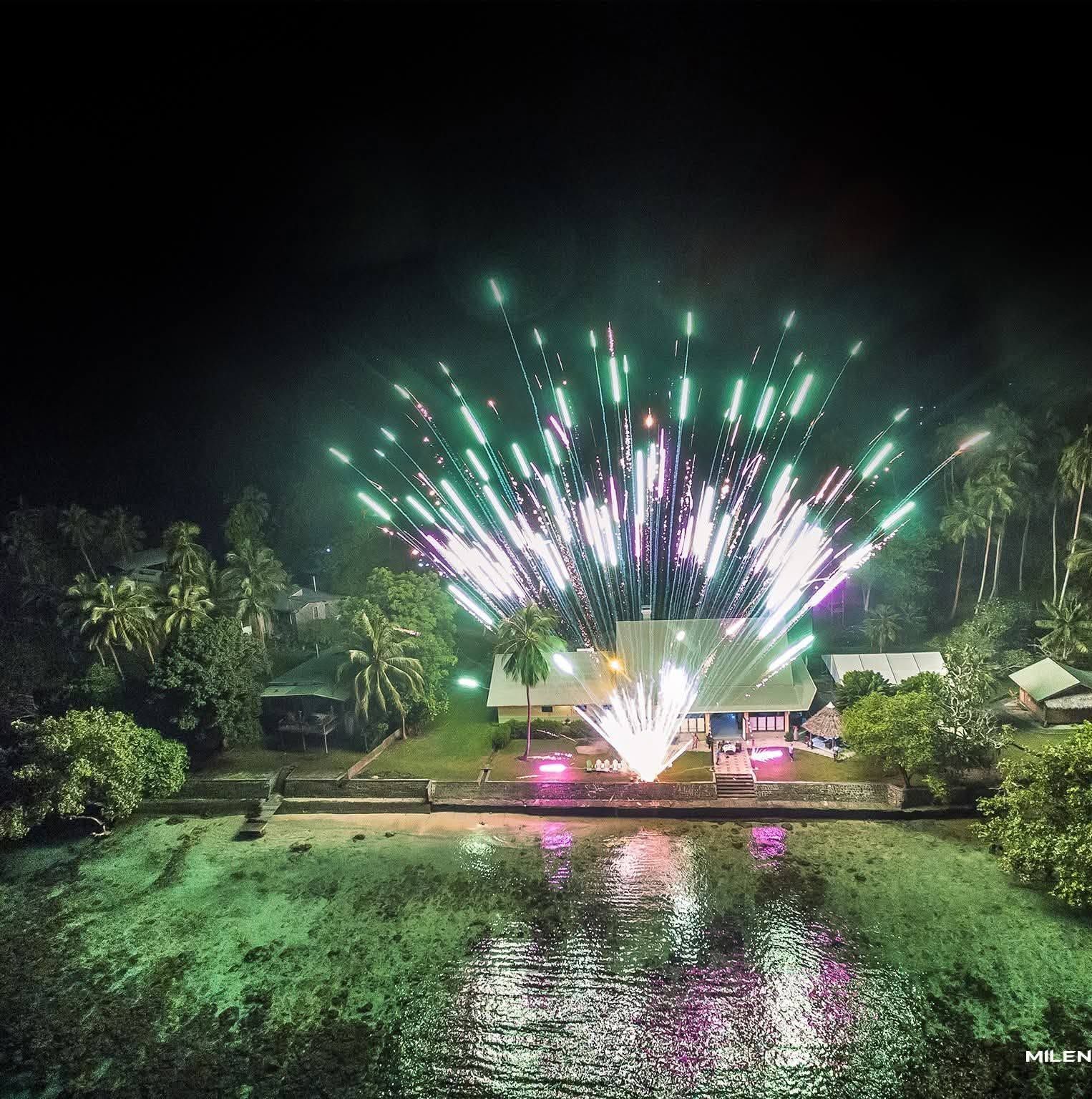 Aerial night view of fireworks over the resort waterfront buildings.
