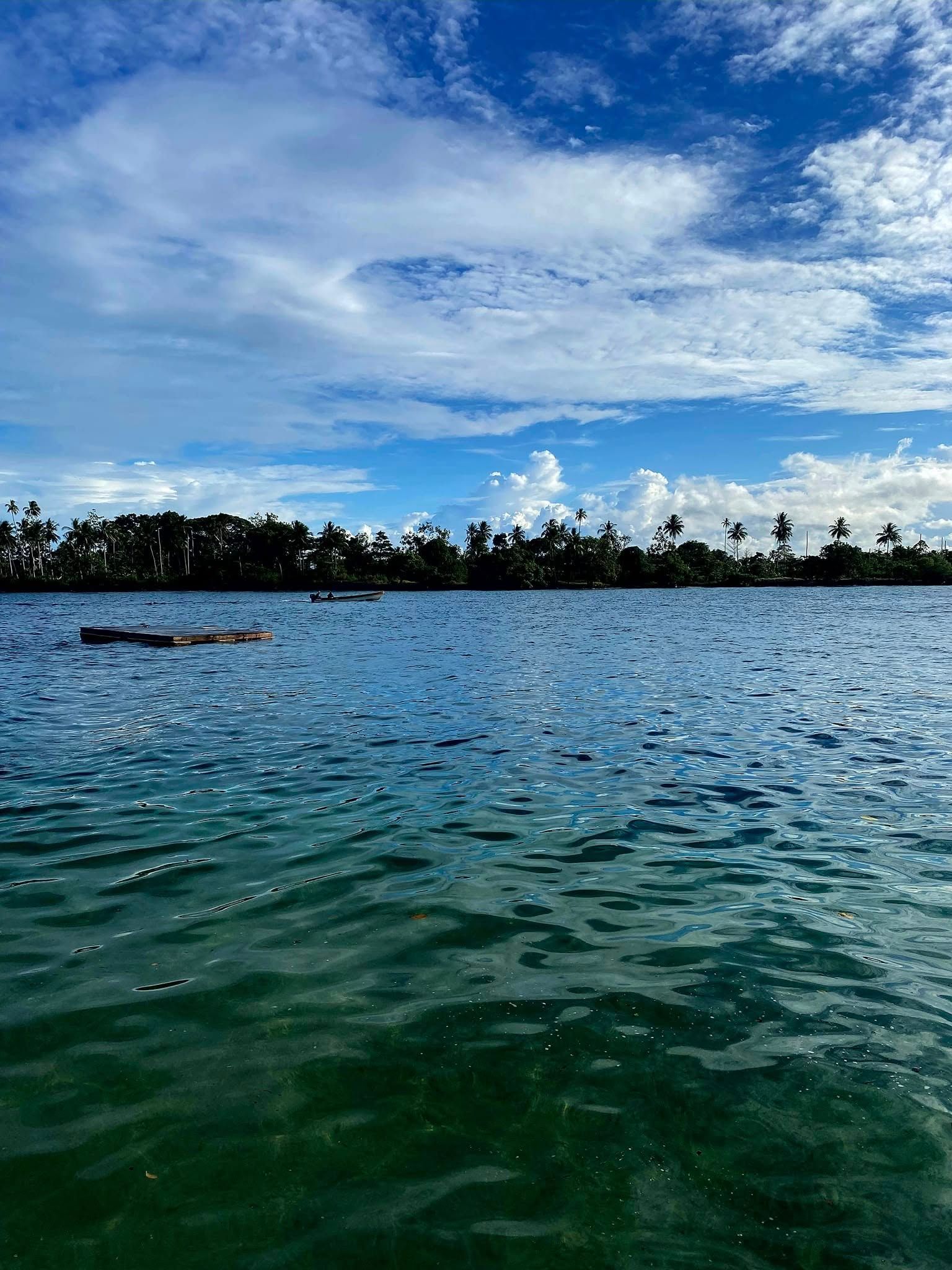 The calm blue bay under a bright sky with fluffy white clouds.