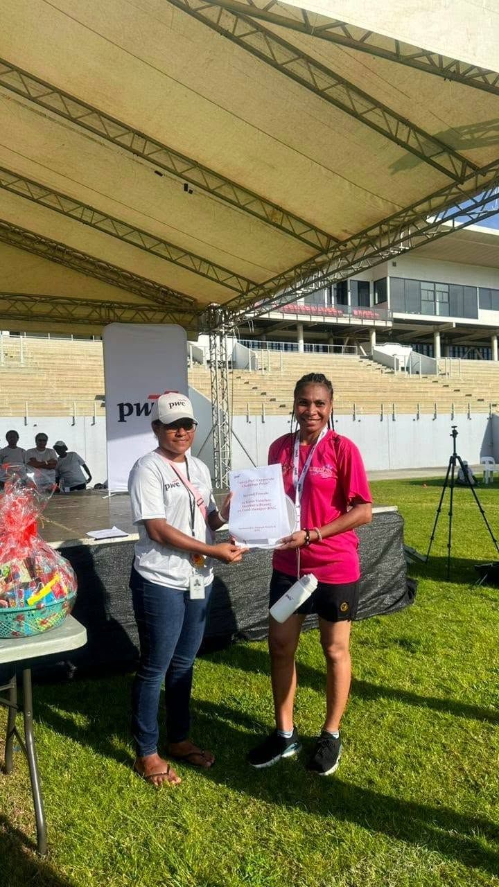 Two women holding a certificate at a corporate event.