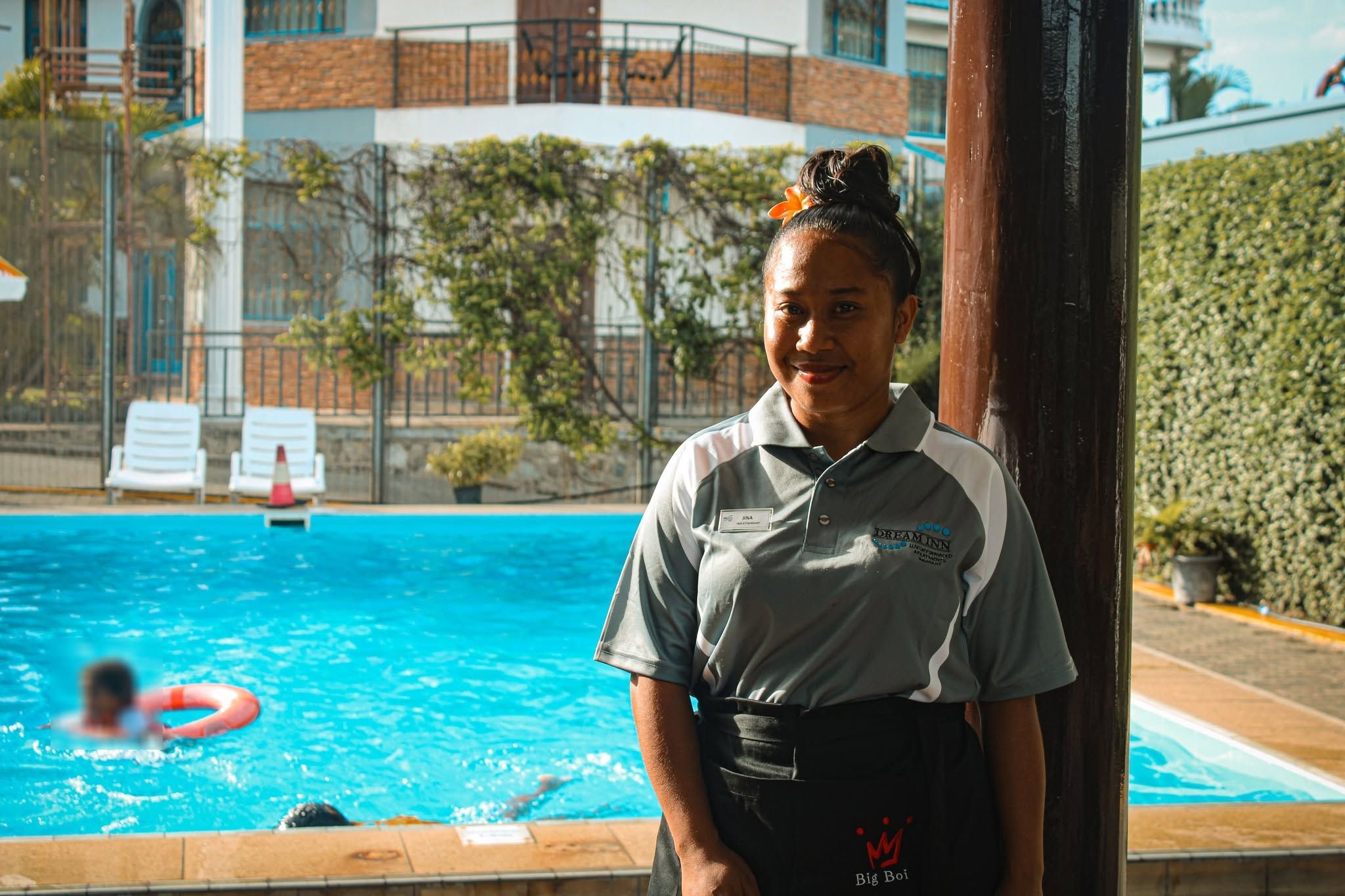 Staff member standing by the poolside area with sun loungers.