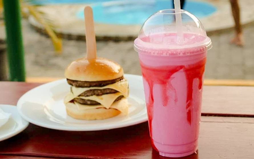 Close-up of a triple cheeseburger and a pink strawberry milkshake.