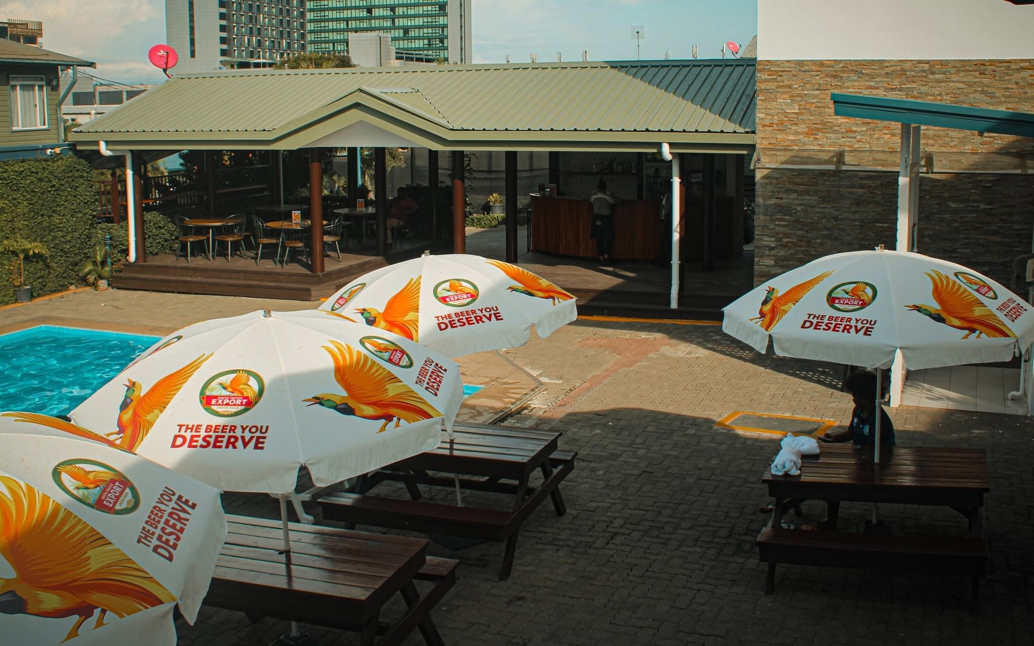 Outdoor bar and dining area with picnic tables and beer umbrellas.
