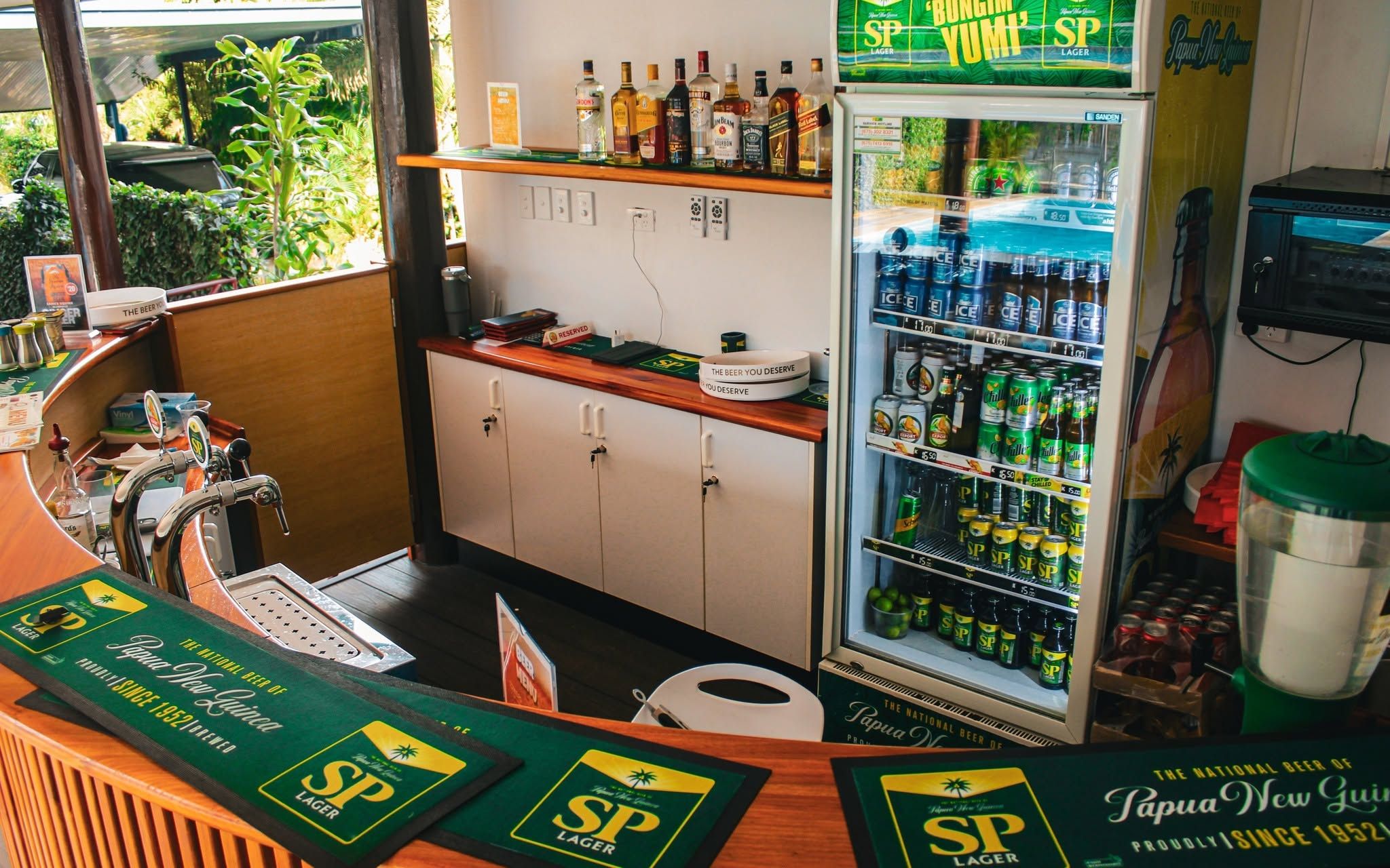 Indoor bar area with beverage refrigerators and spirits display.
