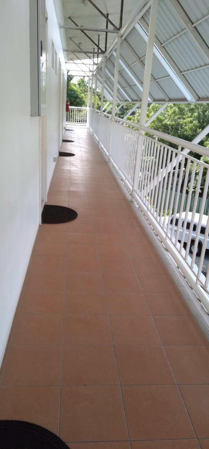 Long tiled outdoor walkway with white railings and covered roof structure.