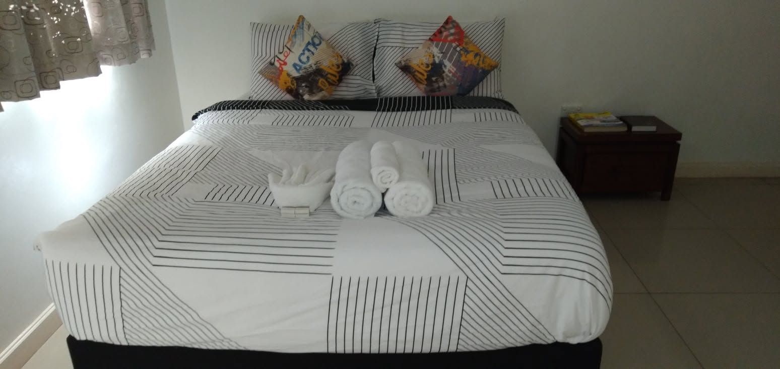 Guest bedroom featuring a large bed with patterned linens and rolled towels.