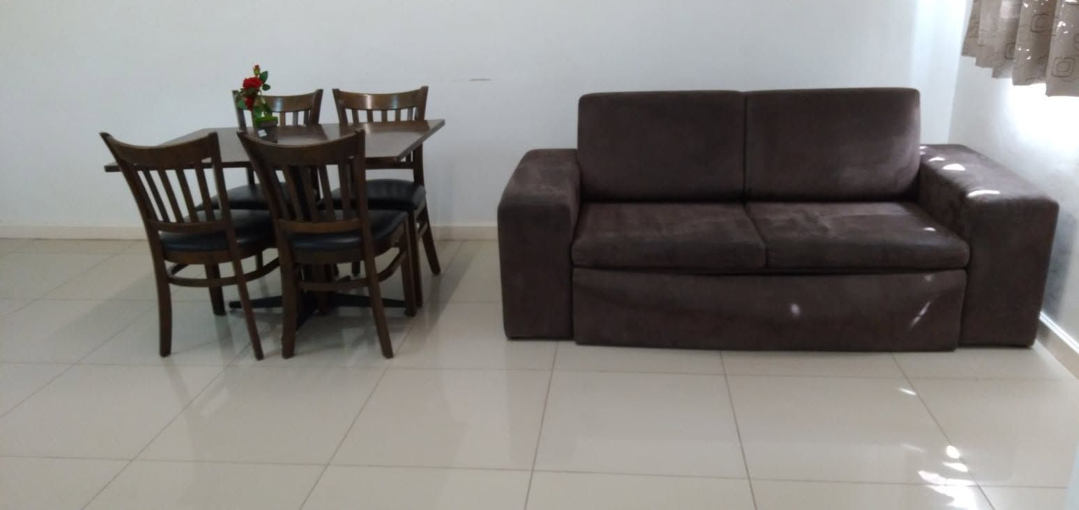 Apartment living space with a dark brown sofa and dining table for four.