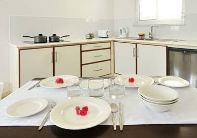 Close-up of a set dining table with white dinnerware and kitchen background.