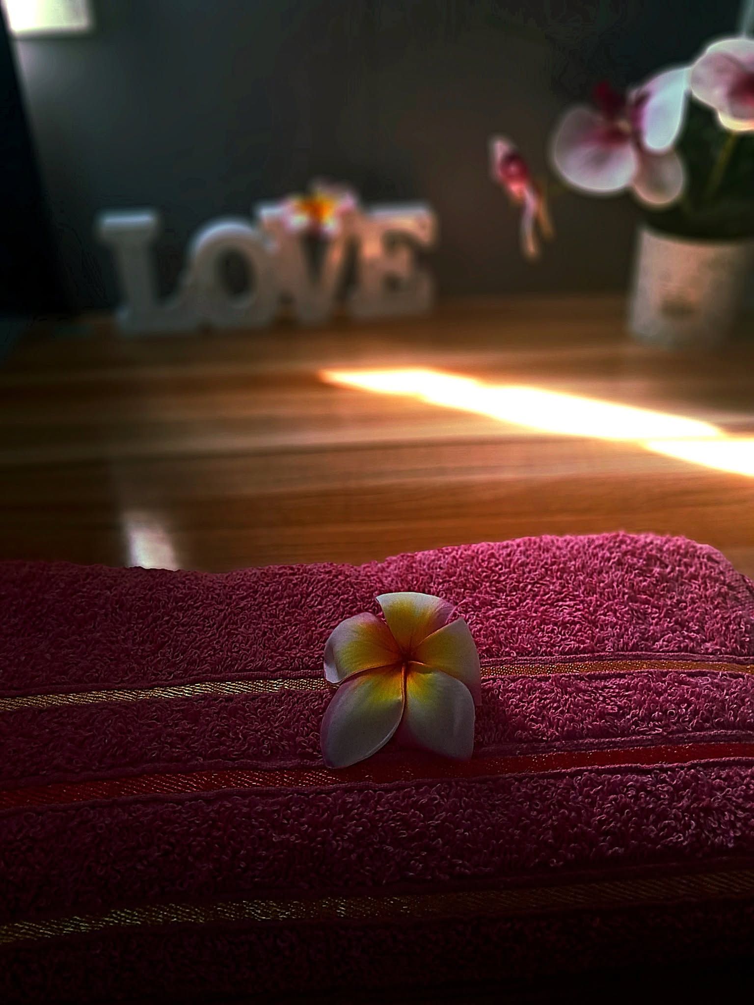 Bed linen detail with a frangipani flower and decorative towel.