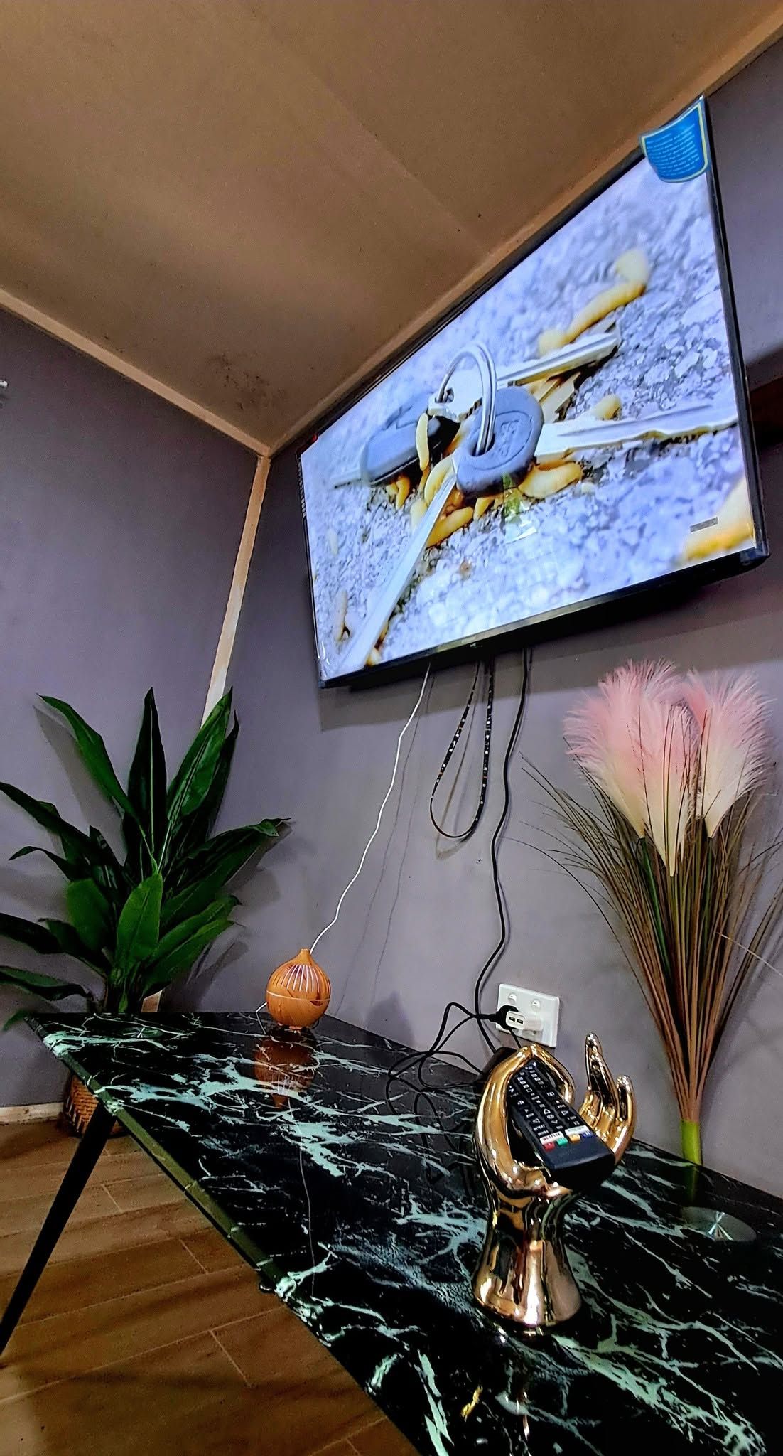 Wall-mounted television above a marble-top table with decor.