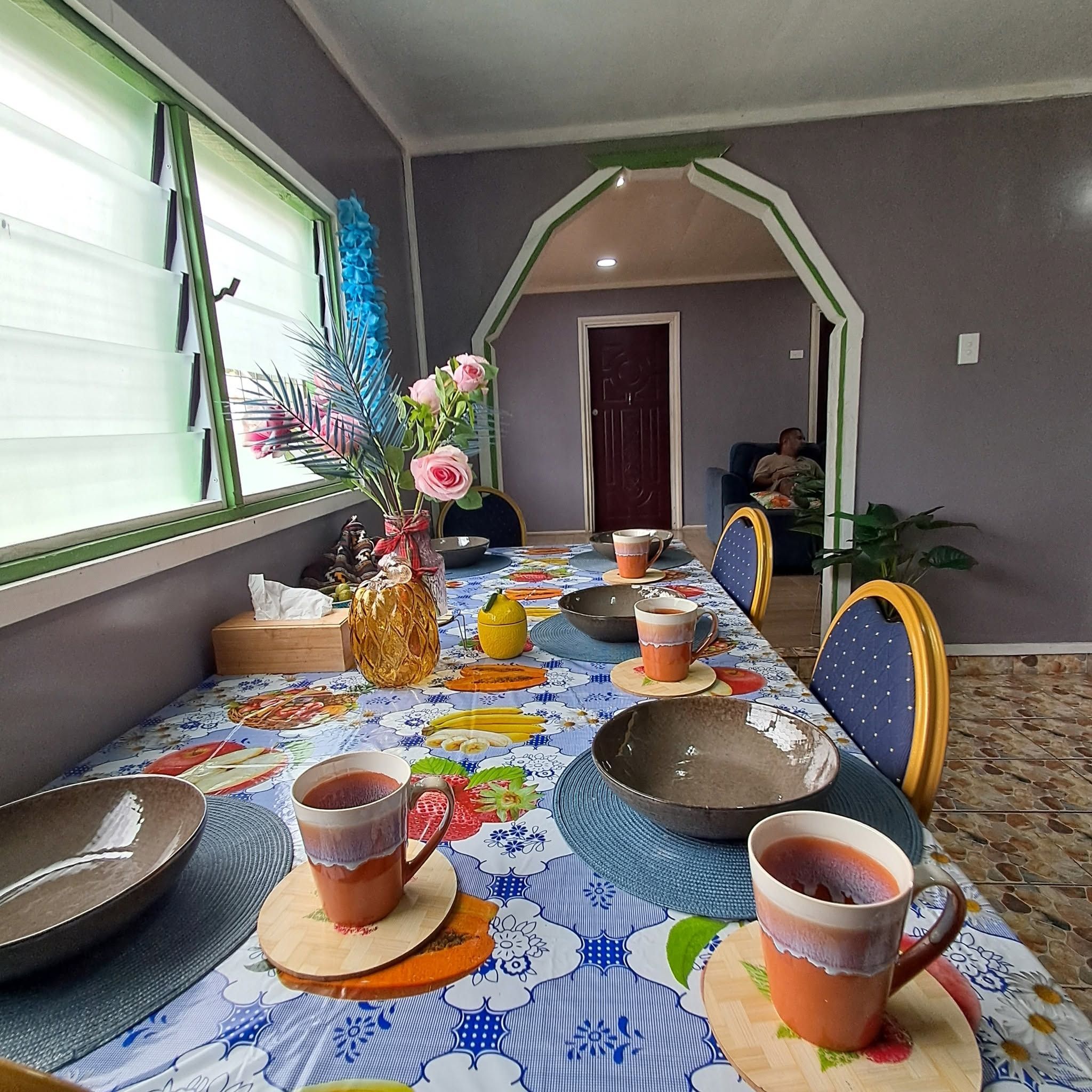 Set dining table with colorful patterned cloth and ceramic mugs.