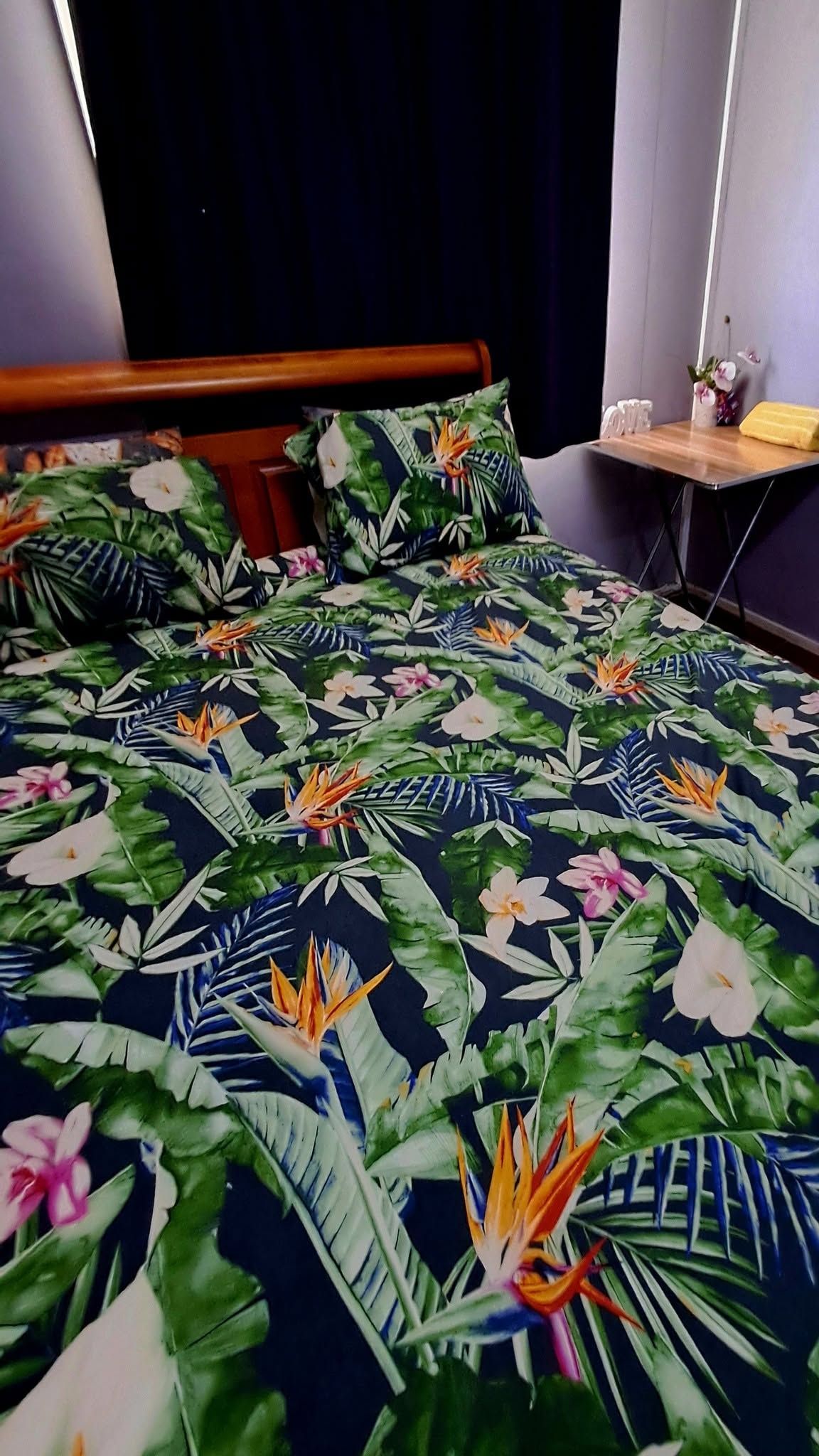 Bedroom featuring a wooden headboard and tropical print bedding.