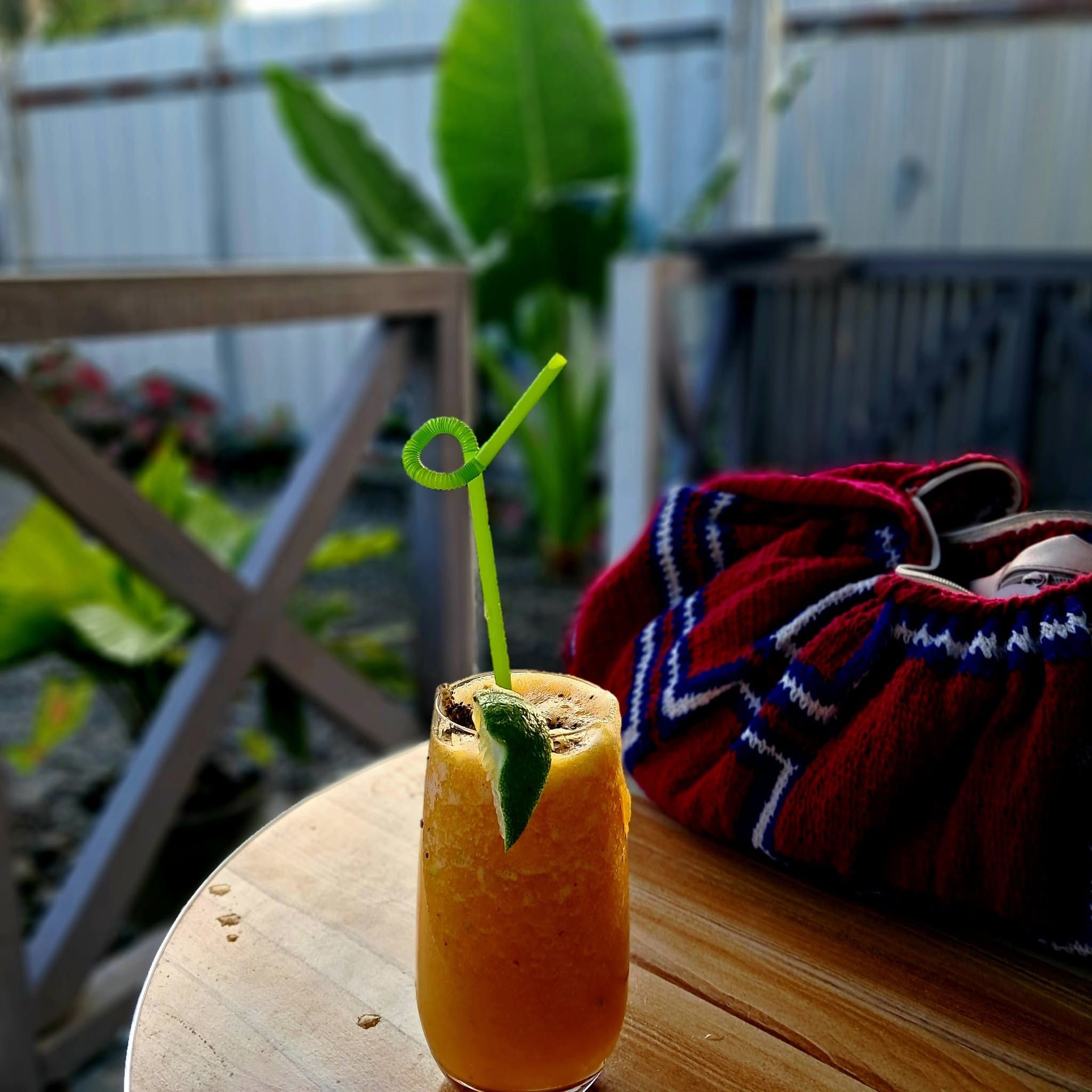 Chilled citrus drink with a straw on a wooden outdoor table.