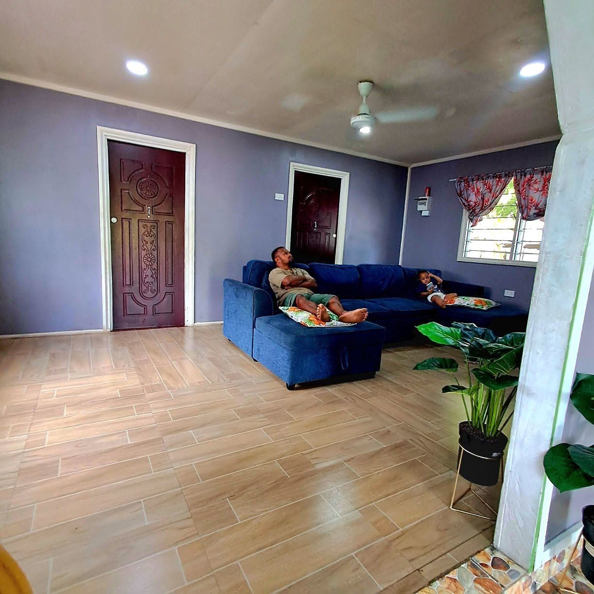 Shared lounge area with blue sectional sofa and tiled flooring.