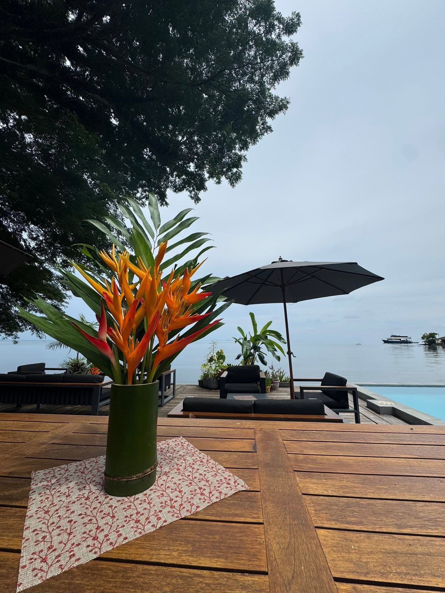Tropical flowers on a dining table overlooking the infinity pool and ocean.