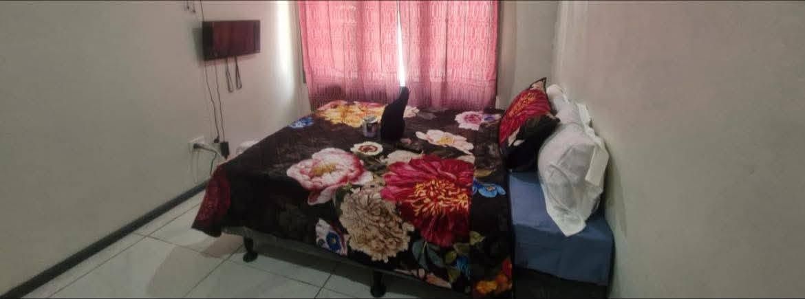 Standard guest room featuring a bed with floral bedding and pink curtains