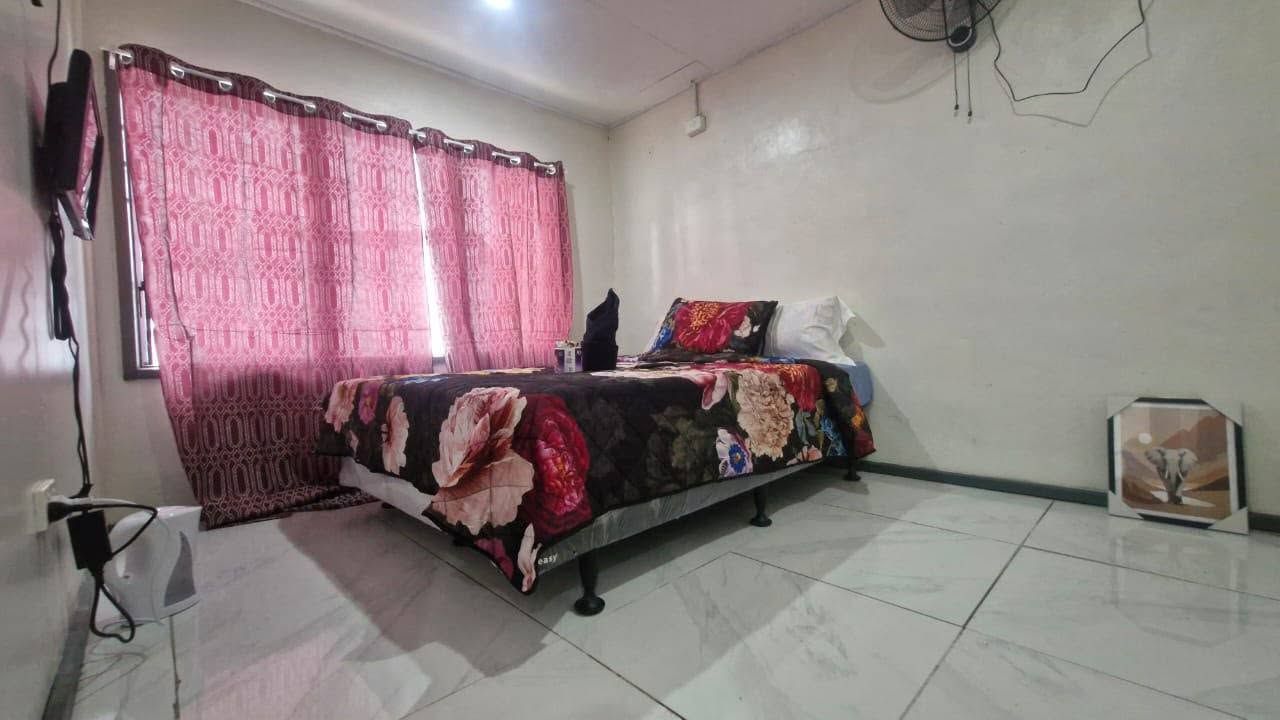 Spacious guest room with tiled floor, wall fan, and large windows