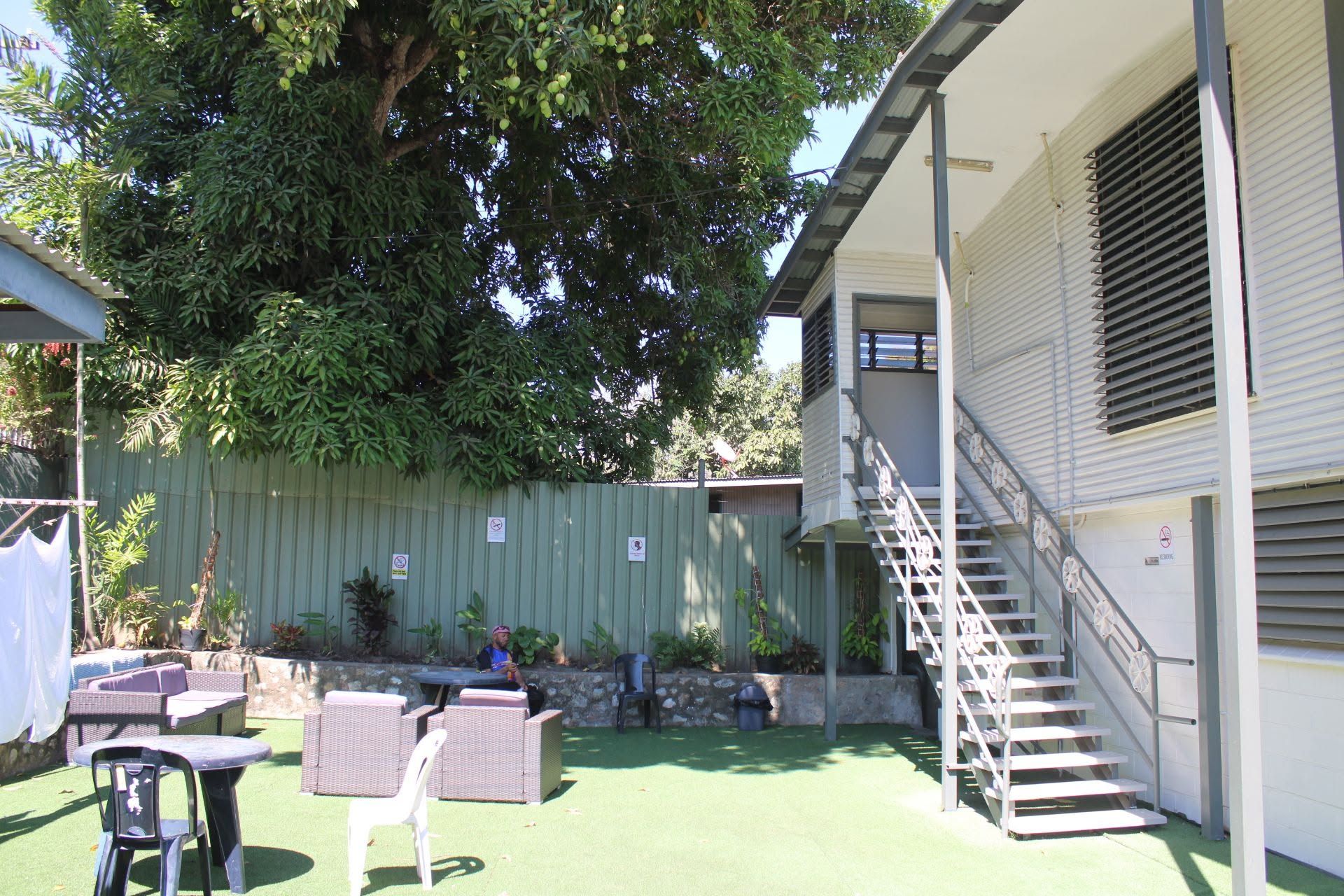 Wicker furniture in the outdoor common area under a large shade tree