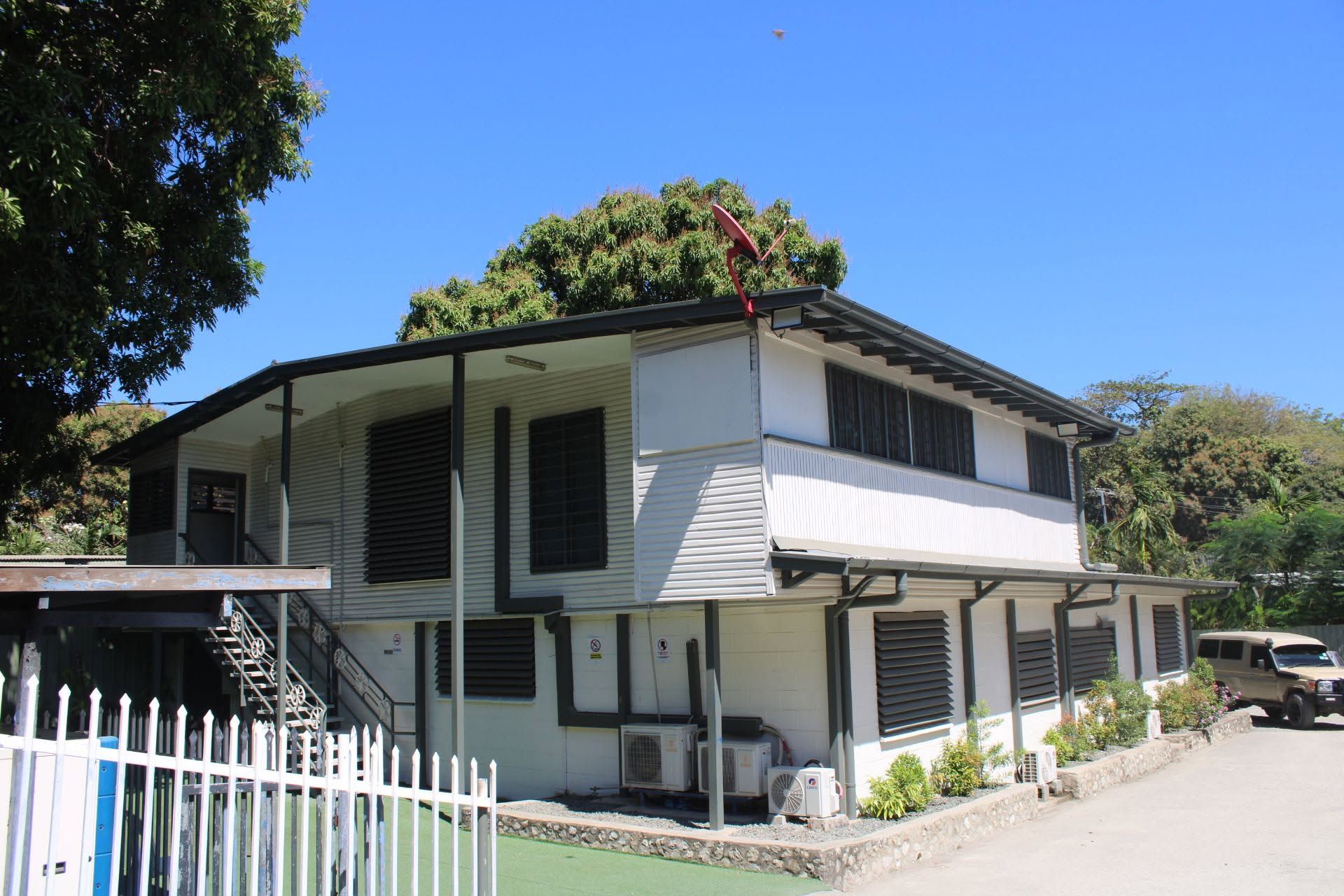 Side facade of the motel building featuring louvred windows and white fencing