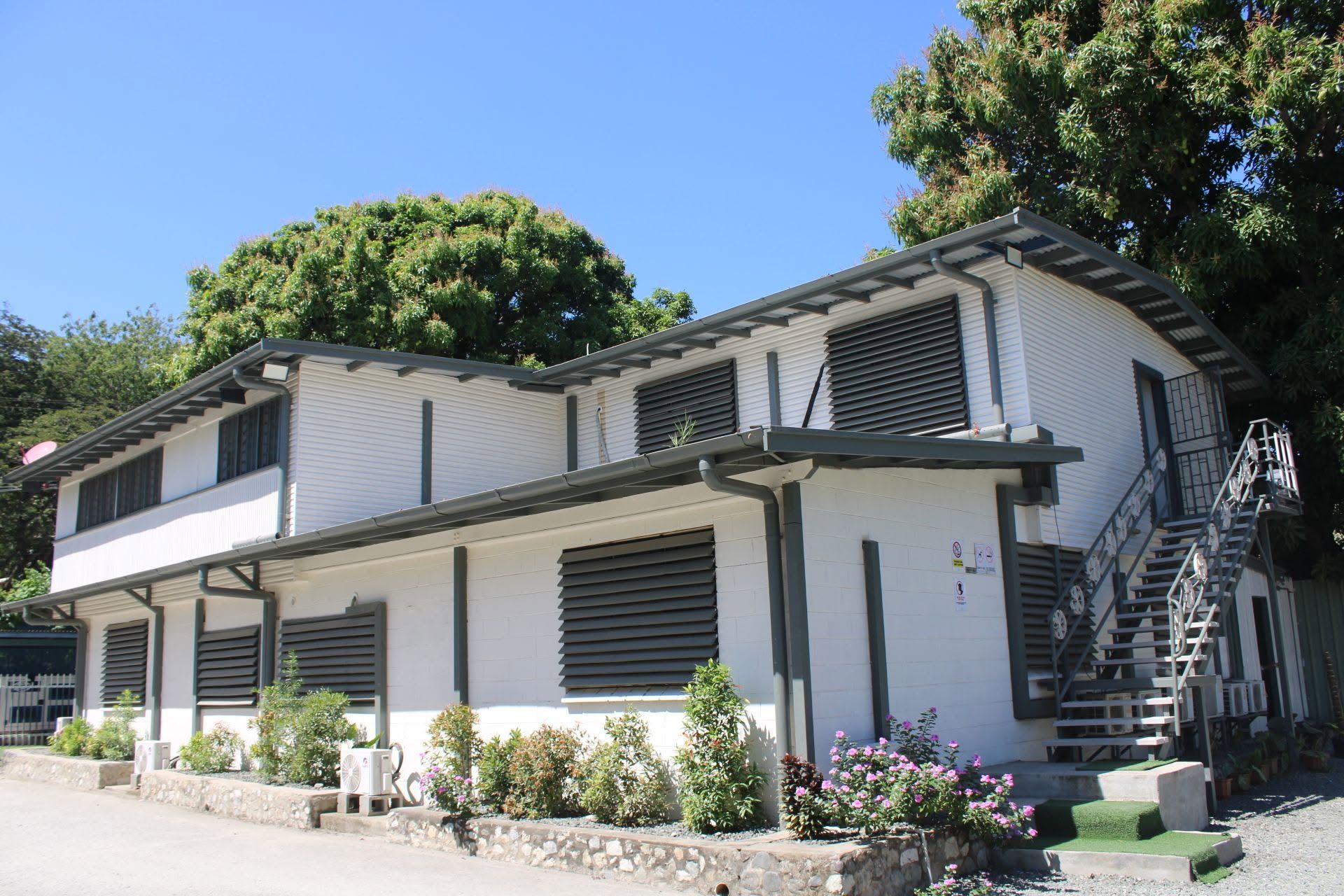 Motel building exterior with manicured flower beds and external staircases