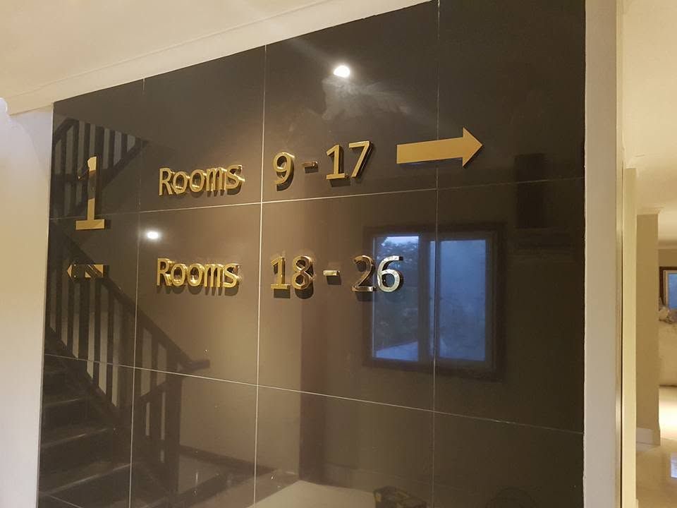 Directional signage on a polished black wall leading to guest rooms.