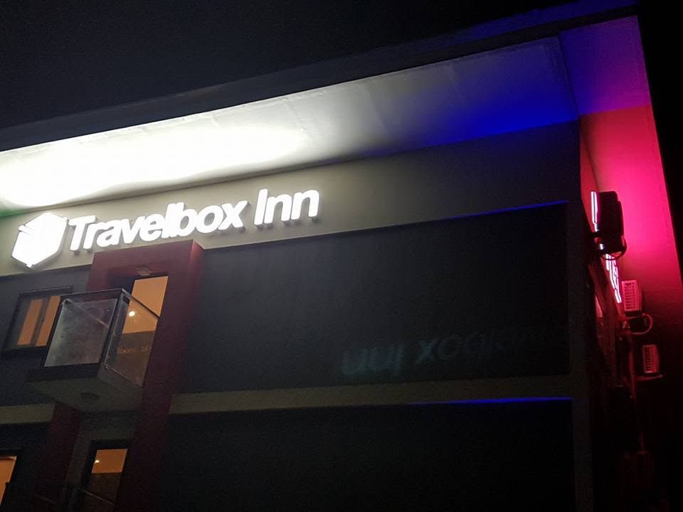 Close-up of the illuminated Travelbox Inn building sign at night.